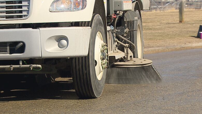 a close up picture of the side sweeping broom on a city street cleaner in action.