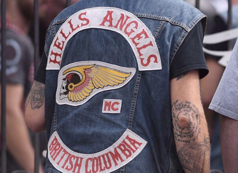 Two people wearing Hells Angels jackets are pictured with their back to camera.