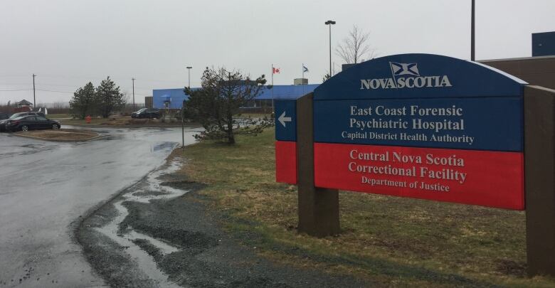 A long low building is seen behind a sign that reads 