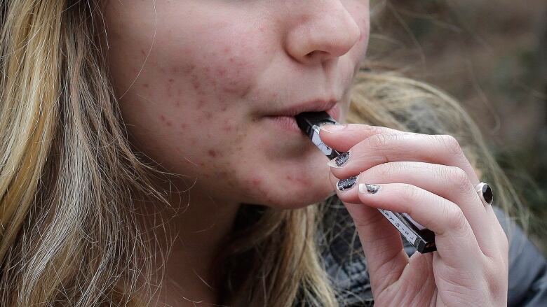  an unidentified 15-year-old high school student uses a vaping device.