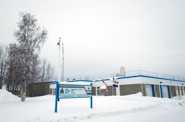 An RCMP sign is seen in front of a 1-storey building, on winter's day.