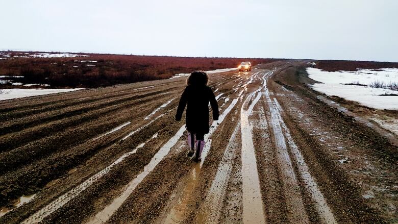 A person walks down the Inuvik Tuktoyaktuk Highway. It was closed due to rainy and muddy conditions in May 2018. 