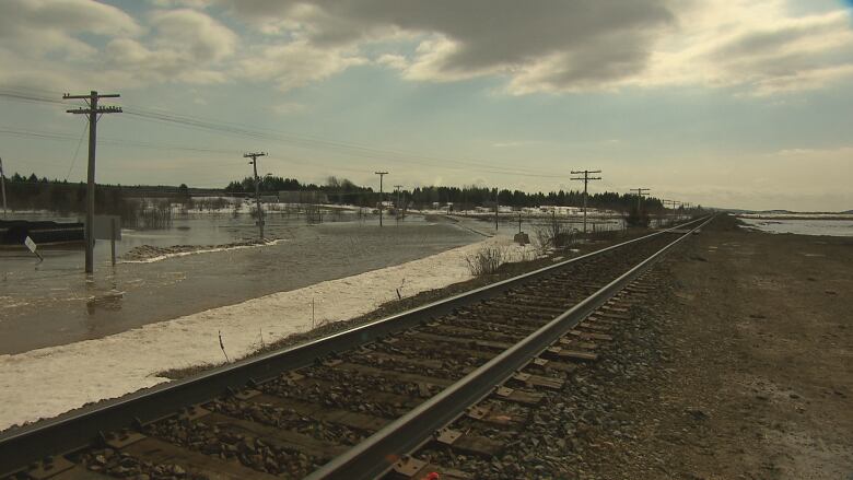 Railroad tracks are pictured on the right, with water, snow and submerged utility poles on the left.