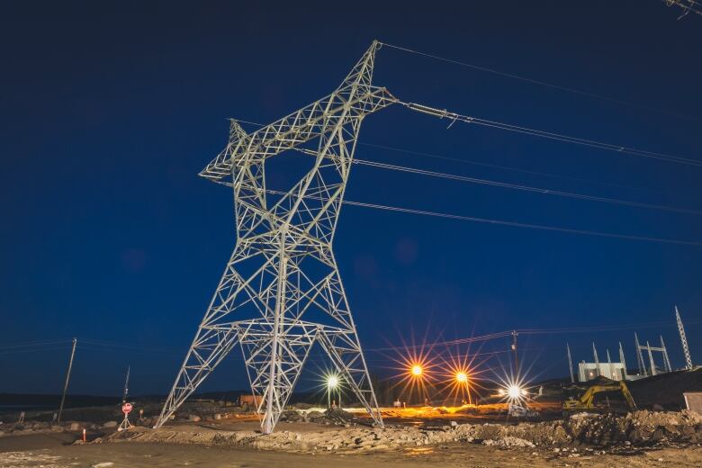 A transmission tower at night, powerful cables of the Labrador-Island Link stretching off into the distance.