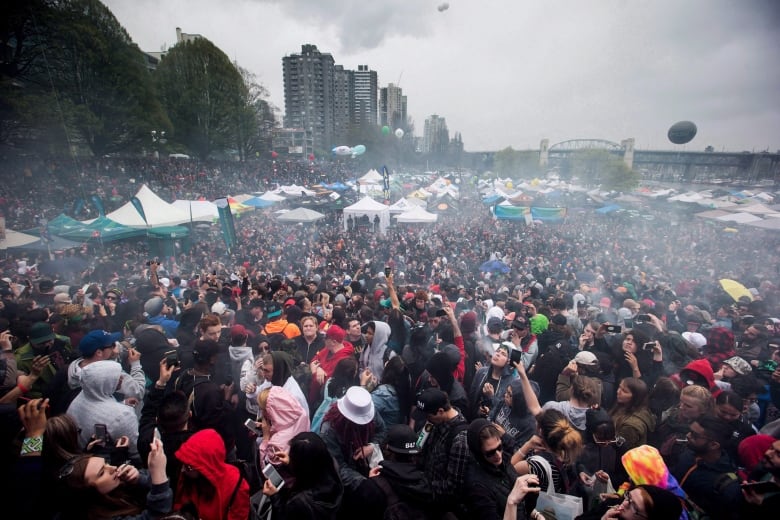 A cloud of smoke hangs over the crowd as thousands of people smoke marijuana during the annual 4/20 marijuana celebration in Vancouver on April 20, 2018.