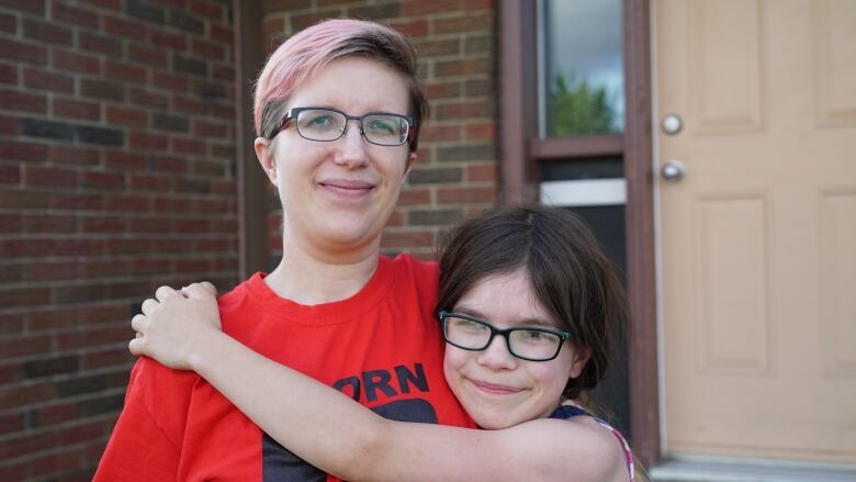 A mother and her nine-year-old daughter outside their home.