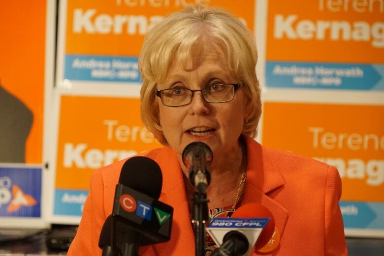 Peggy Sattler sits behind a microphone. 