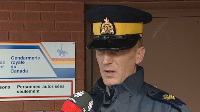 An RCMP officer speaks into a microphone at a detachment. 