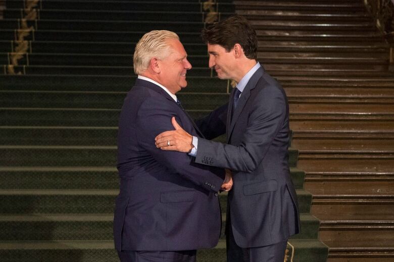 Two men in suits shake hands.