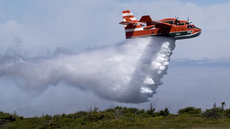 A provincial water bomber douses a fire with water