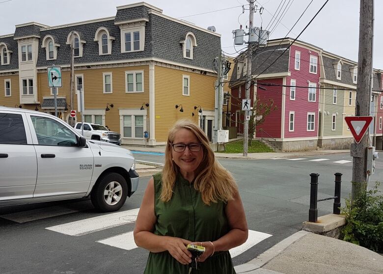 Woman with blond hair standing at crosswalk.