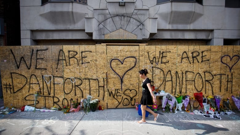 A woman walks by a wall emblazoned with the words 