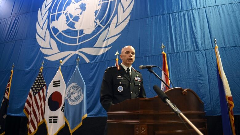 A bald man speaks at a podium.