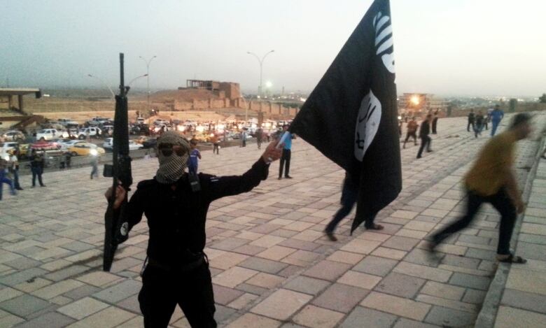 An ISIS fighter holds the group's flag and in the city of Mosul, Iraq, on June 23, 2014.