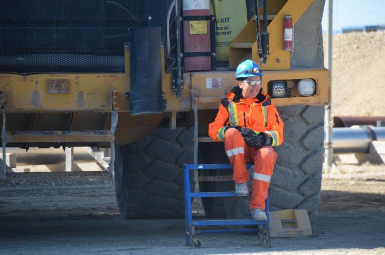 A mining worker sitting next to a truck.