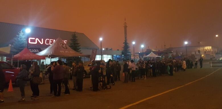 Wildfire evacuees line up for support in Prince George during wildfires in August 2018. The sky is dark orange.