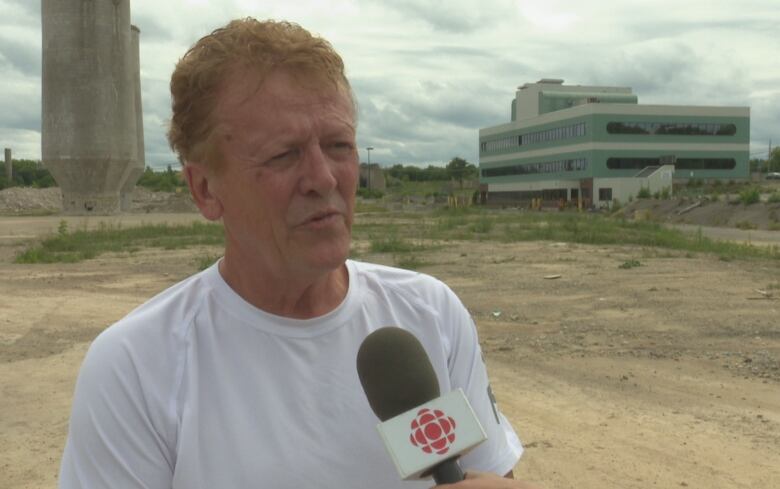 Raymond Robichaud stands in front of the former mill site in Bathurst.