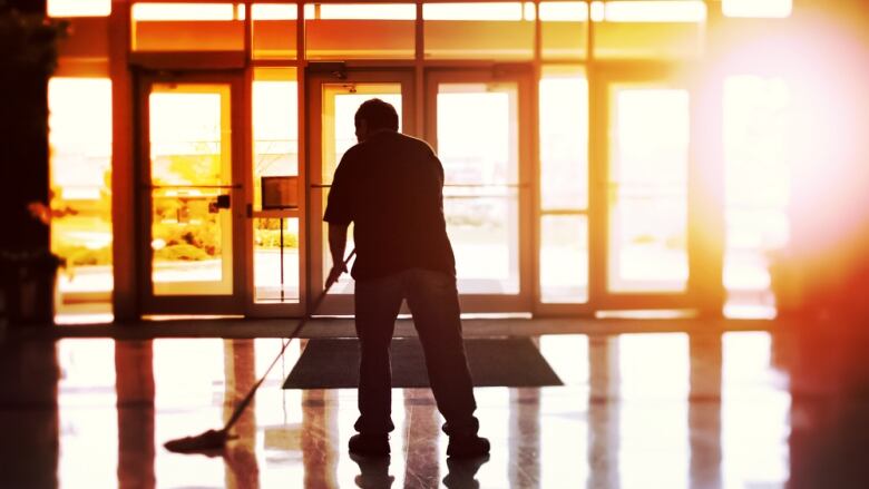 A man is shown mopping a floor.