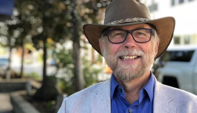 A smiling man wearing a suit and a cowboy hat