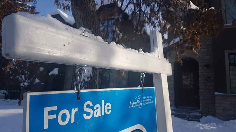 A snow-covered sign advertising a house for sale in Calgary.