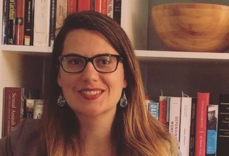 Suzie Dunn stands in front of a bookshelf.