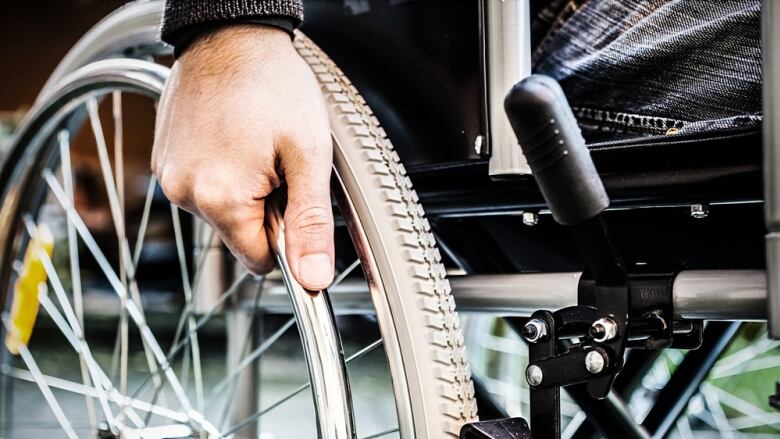 Close up of a person's hand on a wheelchair wheel.