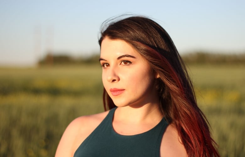 A woman stands in a field.