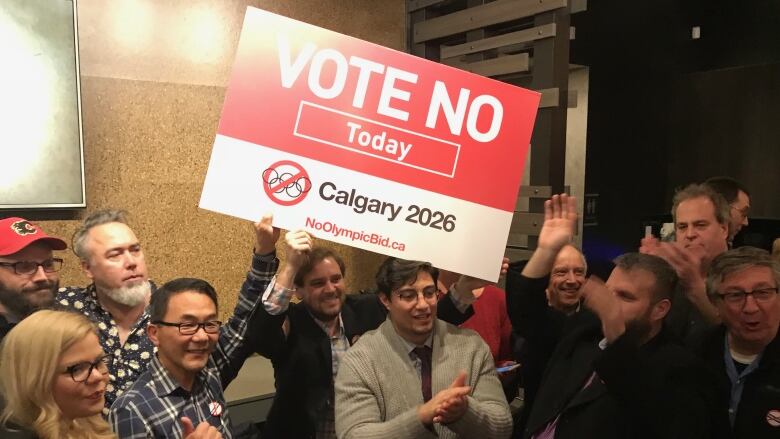 A group of people holding a sign that reads ' Vote No Today Calgary 2026' look happy.