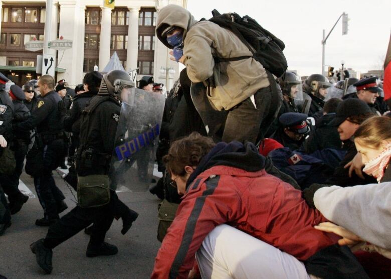 Police confront people trying to climb a barricade 