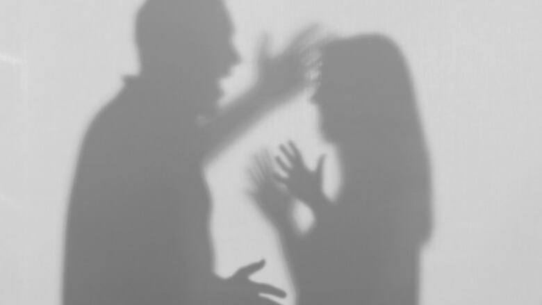 The shadows of what looks to be a man and a woman fighting show up on a wall.