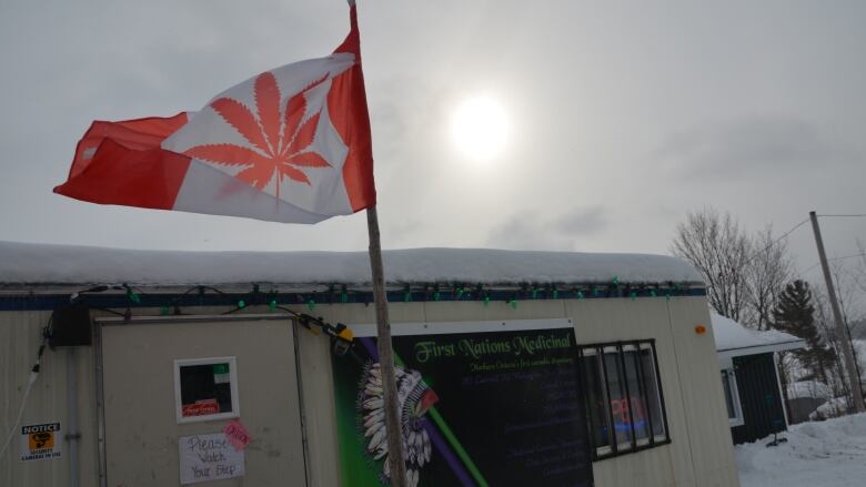 A trailer covered in snow with a Canadian flag featuring a marijuana leaf