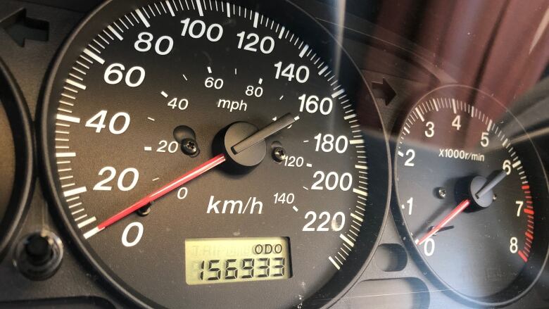 A car odometre is shown reading 156,933 kilometres.