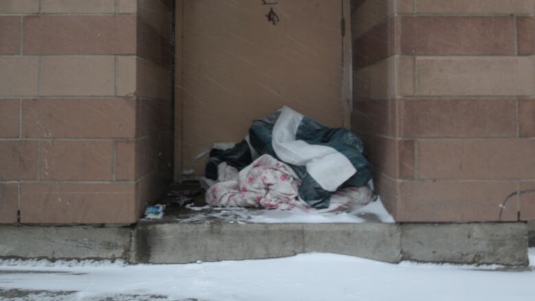 A pile of blankets gathers snow inside a doorway in downtown Hamilton.