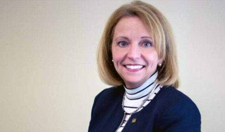 A woman in a blue blazer poses for a photo.