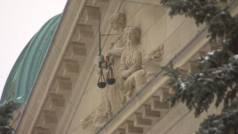 A statue depicting the scales of justice on the exterior of Winnipeg's Law Courts building.