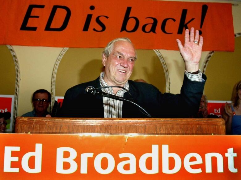 A man waving from a lectern after winning an election.