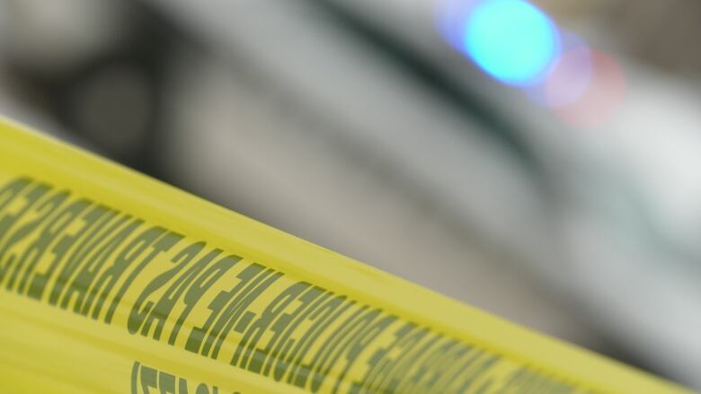 A closeup picture of yellow police tape with blurred lights in the background