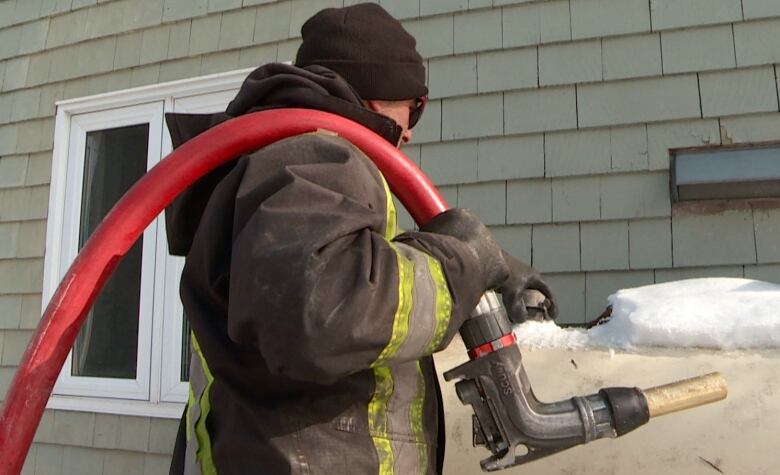 A worker fills a home heating oil tank on a snowy day 