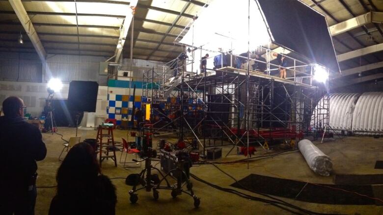 Lights and scaffolding for a film shoot are set up inside an old arena.