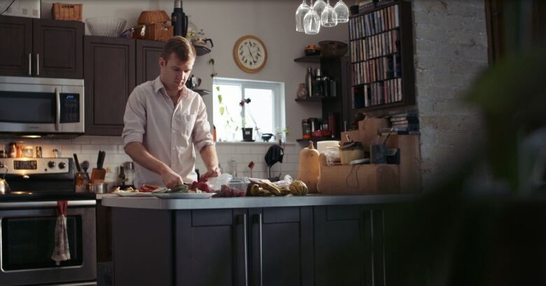 A man at a counter chops vegetables in a kitchen.