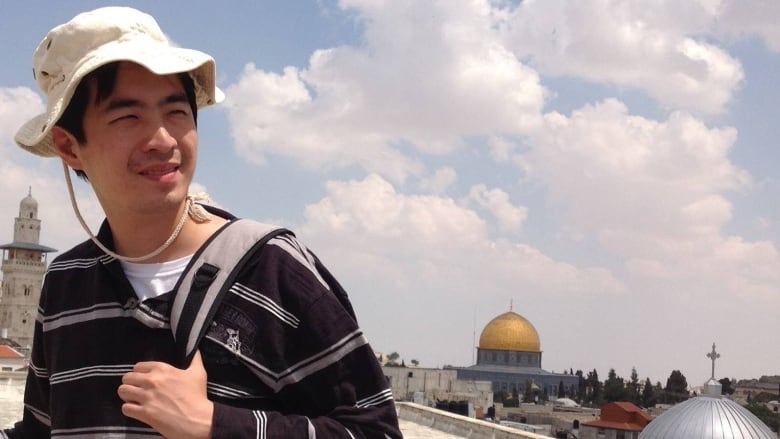 A man in a bucket hat poses for a photo while on vacation. 