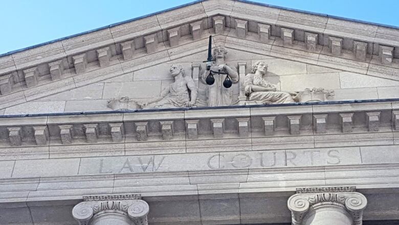 The exterior of a grey stone building with pillars and the engraved words 