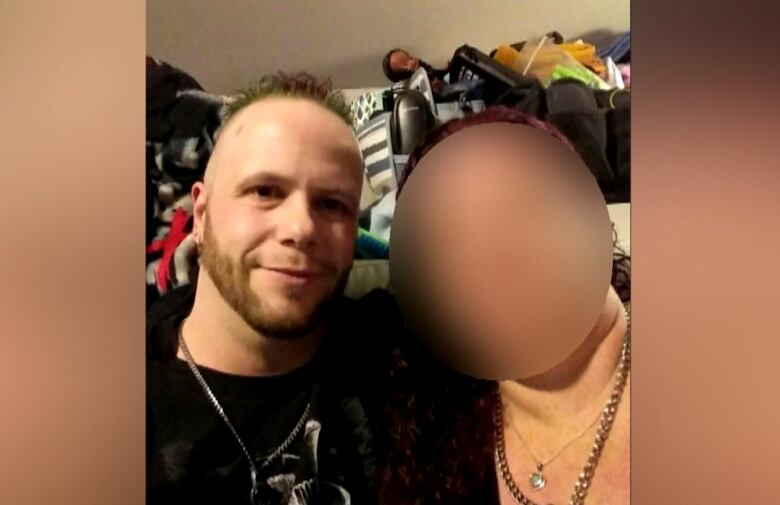 A selfie of a man and woman sitting on a couch. Her face is blurred.