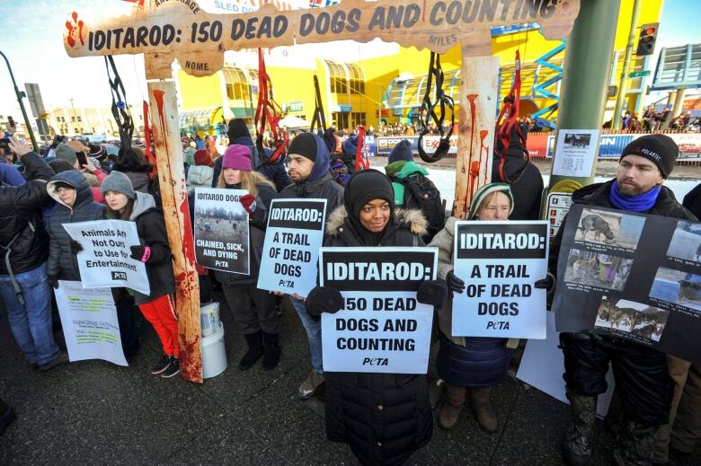 A group of protesters stand outside holding signs.