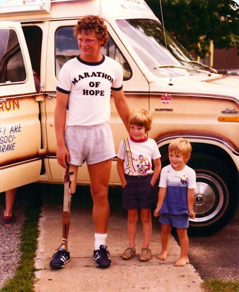 A man poses with two small children.