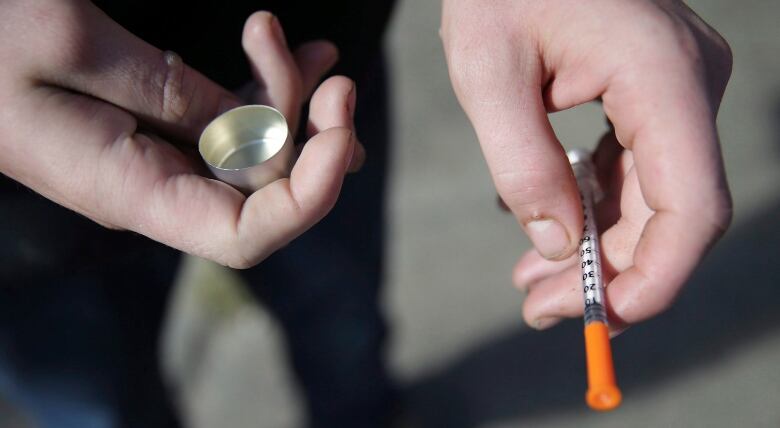 a fentanyl user holds a needle near Kensington and Cambria in Philadelphia