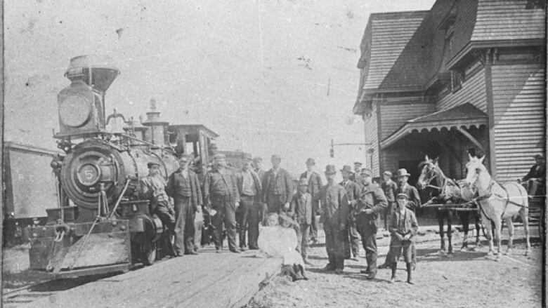 Old black and white photo of train arriving at station.