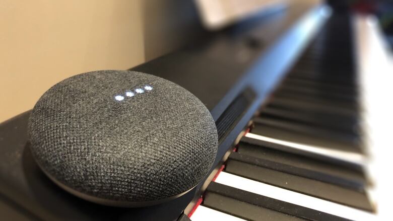 A Google Home device sits on a piano. 