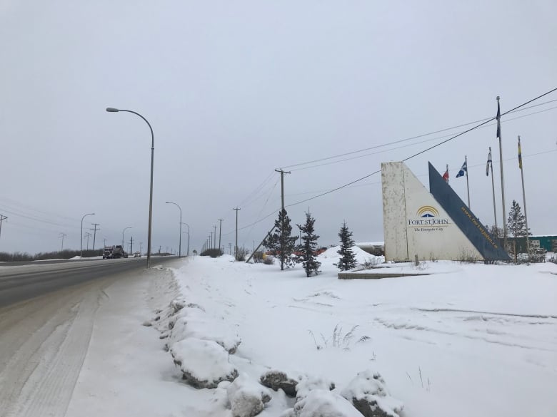 A dirty snow highway is seen with a white cement sign that reads 