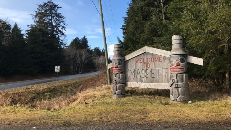 A sign with two small totem poles next to it reads 'Welcome to Massett'.